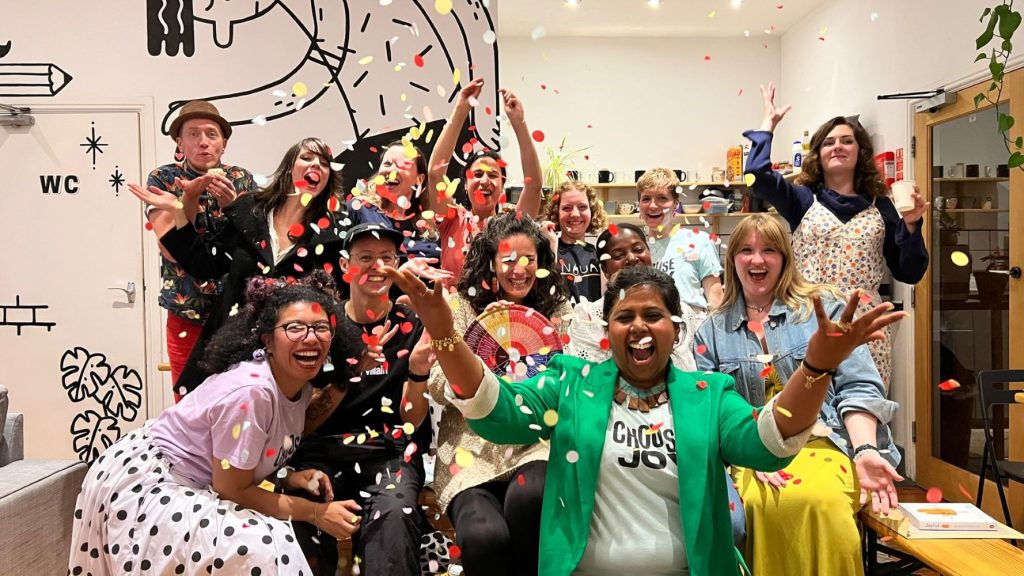 Nisha and cheerful workshop participants smiling as confetti sprinkles around them.