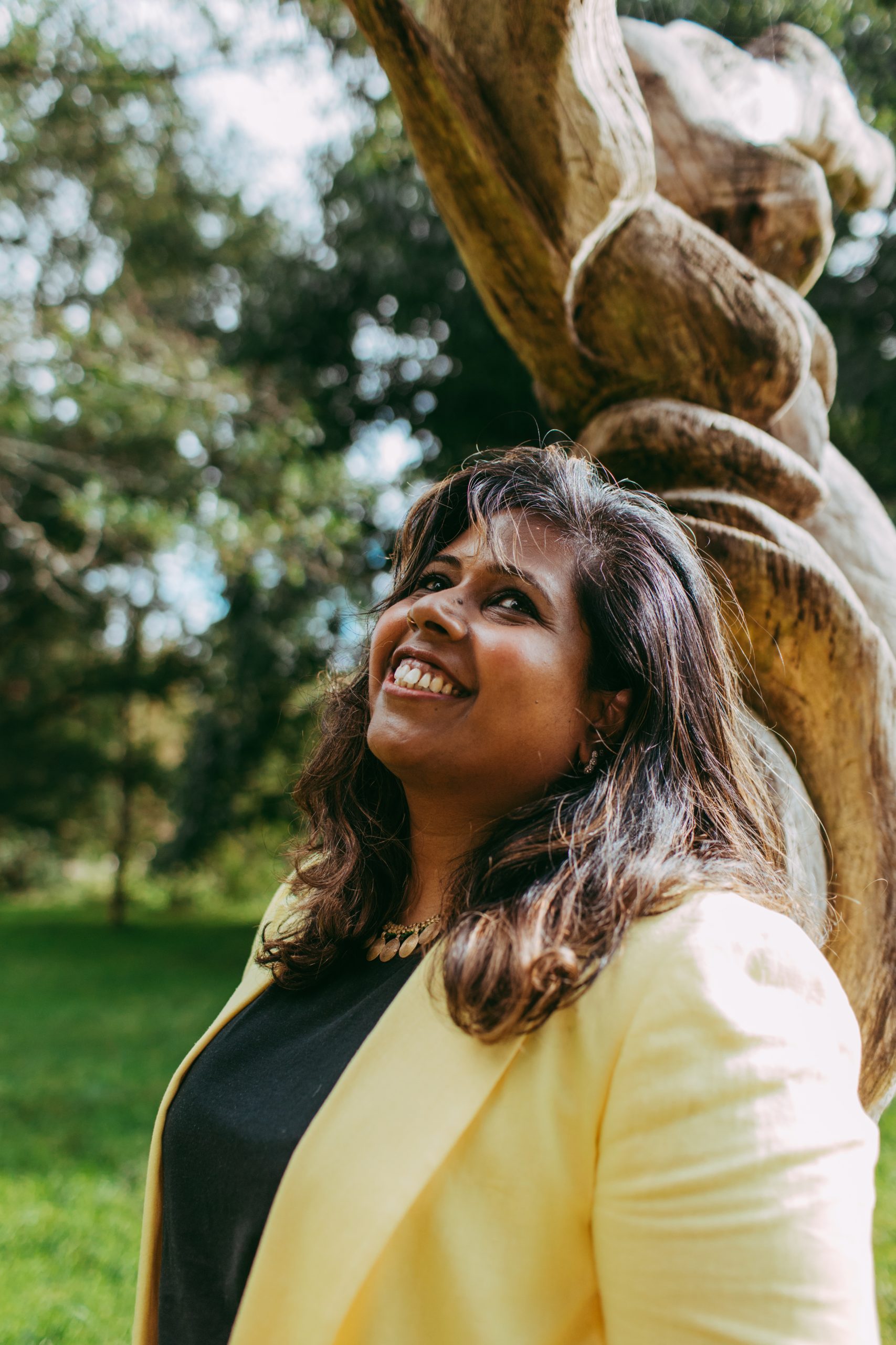 Nisha leaning against a tree in the park.